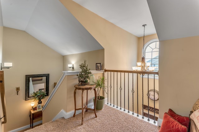 hall featuring carpet floors, an inviting chandelier, and vaulted ceiling