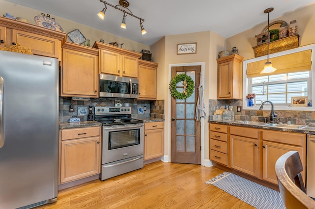 kitchen with light wood-type flooring, stainless steel appliances, tasteful backsplash, and sink