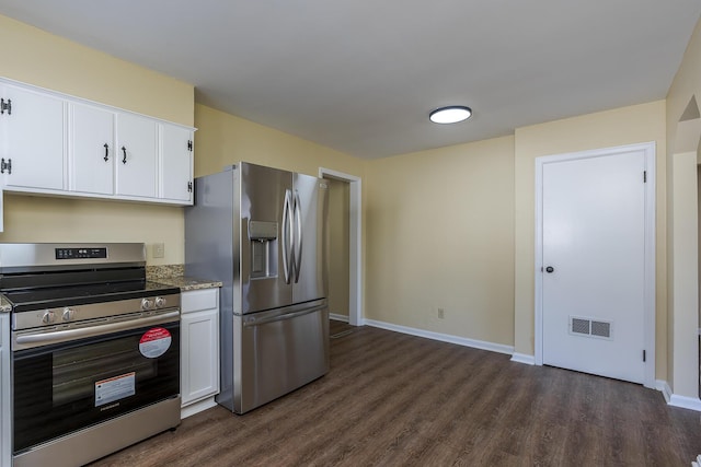 kitchen with dark hardwood / wood-style flooring, white cabinets, dark stone counters, and appliances with stainless steel finishes