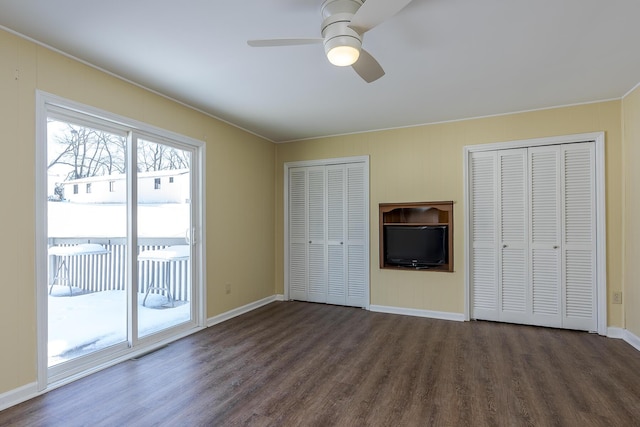 unfurnished bedroom featuring access to outside, dark wood-type flooring, two closets, and ceiling fan