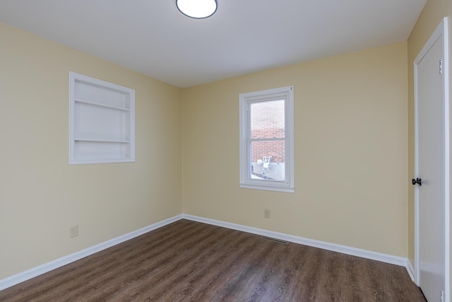 unfurnished room featuring built in features and dark hardwood / wood-style floors