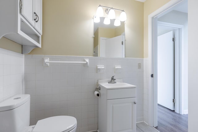 bathroom featuring tile walls, hardwood / wood-style flooring, toilet, and vanity