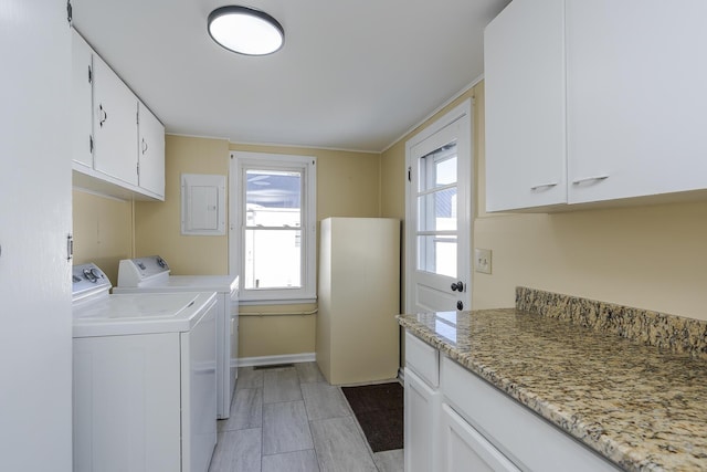 laundry room with electric panel, washer and dryer, and cabinets