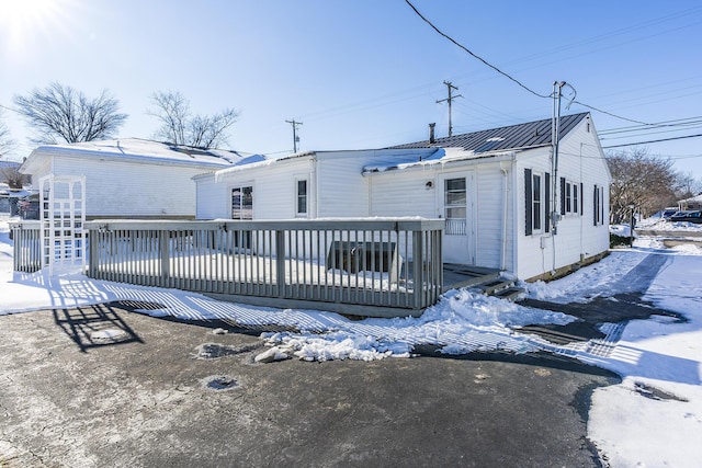 snow covered rear of property with a wooden deck