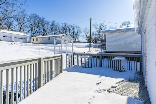 snow covered deck with a garage and an outbuilding