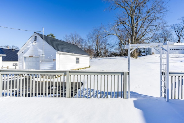 snow covered deck featuring an outbuilding and a garage