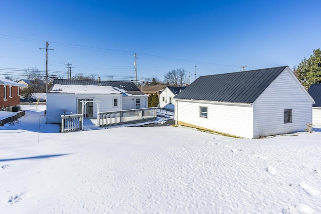 snow covered back of property with a deck