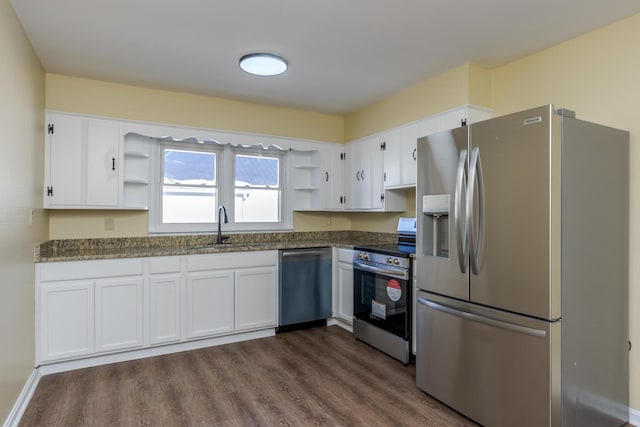 kitchen with appliances with stainless steel finishes, white cabinets, dark stone countertops, and sink