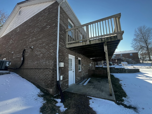 snow covered property featuring cooling unit and a wooden deck