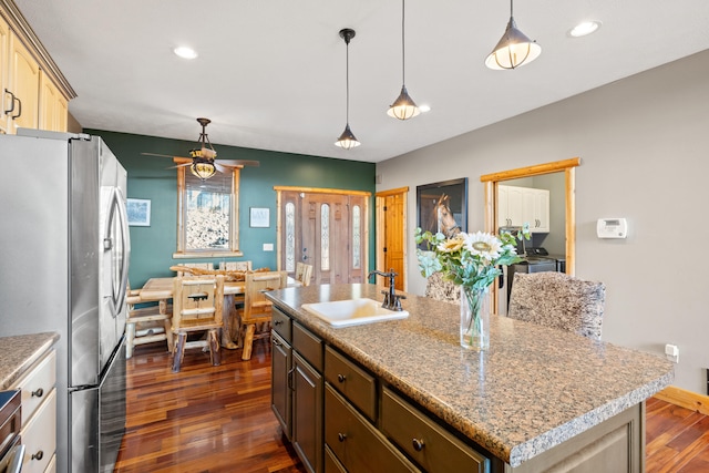 kitchen with sink, decorative light fixtures, ceiling fan, an island with sink, and stainless steel fridge