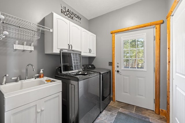 laundry room with sink, washing machine and clothes dryer, a textured ceiling, and cabinets