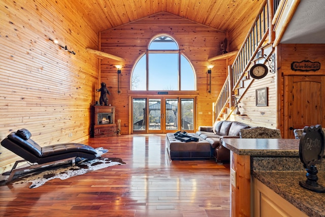 living room with wood ceiling, high vaulted ceiling, and wood walls