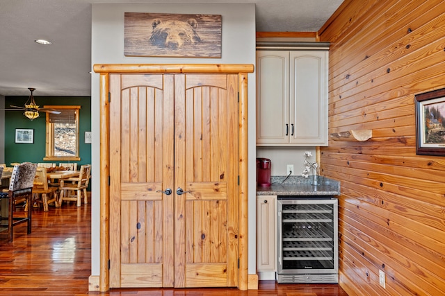 bar with hardwood / wood-style floors, wood walls, ceiling fan, and wine cooler