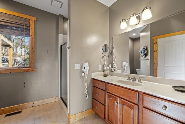 bathroom featuring toilet, tile patterned flooring, vanity, and a shower with shower door