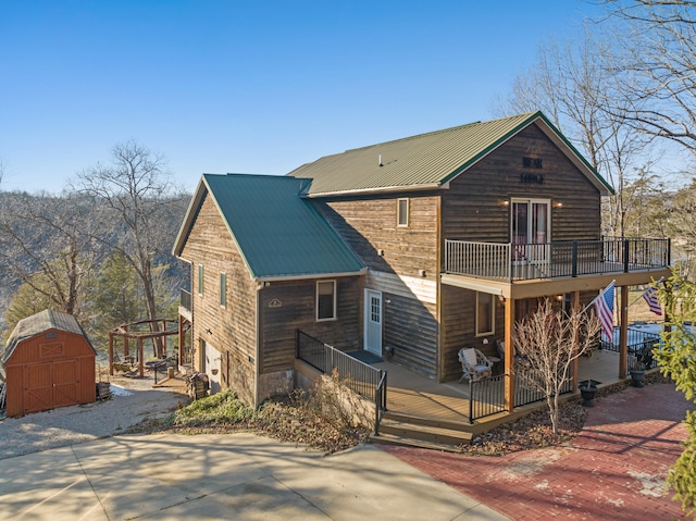 rear view of house with a storage unit and a wooden deck