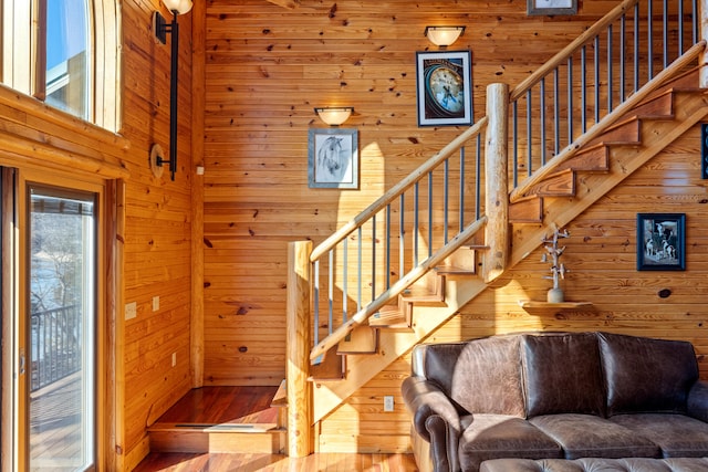 stairs with a towering ceiling, wooden walls, and hardwood / wood-style flooring