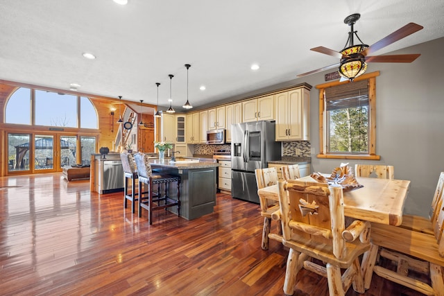 kitchen featuring stainless steel appliances, a kitchen island, tasteful backsplash, and dark wood-type flooring