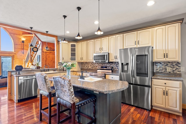 kitchen with a breakfast bar area, stainless steel appliances, kitchen peninsula, dark hardwood / wood-style floors, and decorative light fixtures