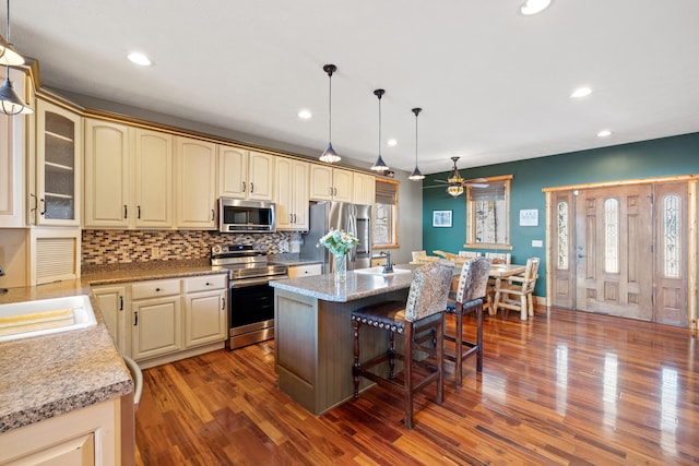 kitchen with appliances with stainless steel finishes, ceiling fan, pendant lighting, a kitchen island, and sink