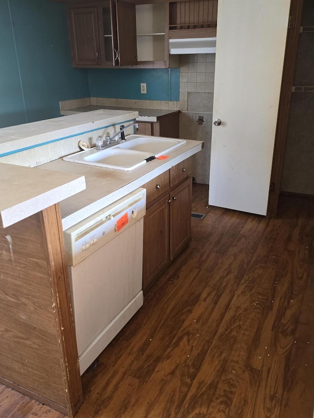 kitchen with dark wood-type flooring, decorative backsplash, dishwasher, and sink