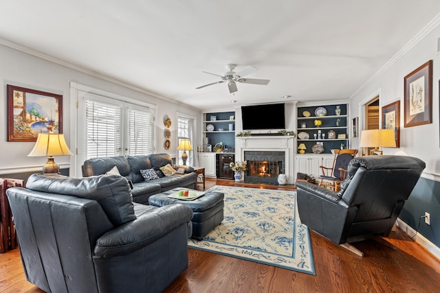 living room with beverage cooler, hardwood / wood-style floors, a tiled fireplace, ceiling fan, and built in shelves