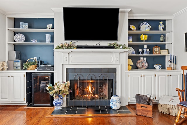 living room with built in shelves, crown molding, a fireplace, and wine cooler