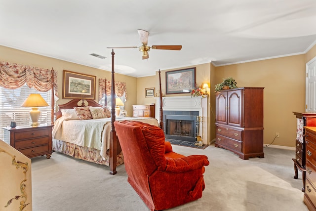 bedroom with ceiling fan, light colored carpet, ornamental molding, and a tile fireplace