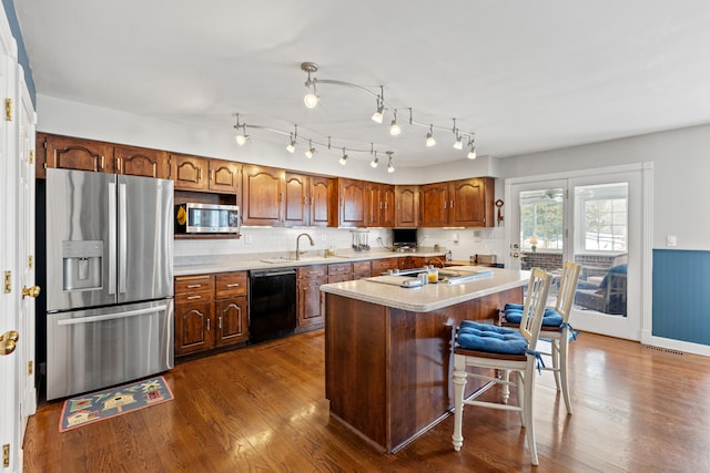 kitchen with stainless steel appliances, dark wood-type flooring, a kitchen island, sink, and backsplash