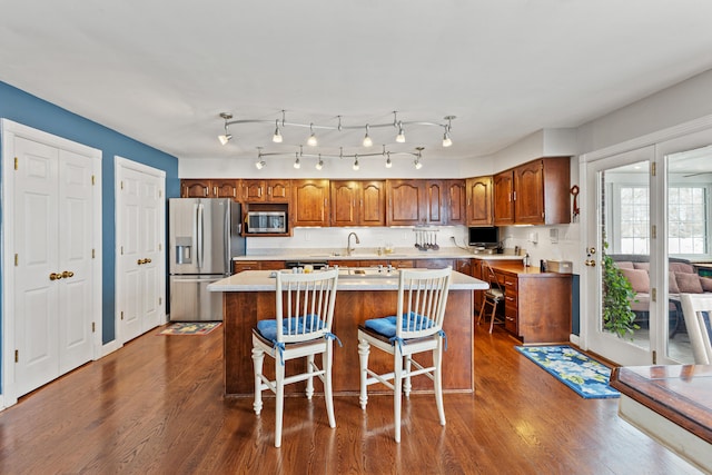 kitchen with a kitchen island, stainless steel appliances, dark wood-type flooring, and a kitchen bar