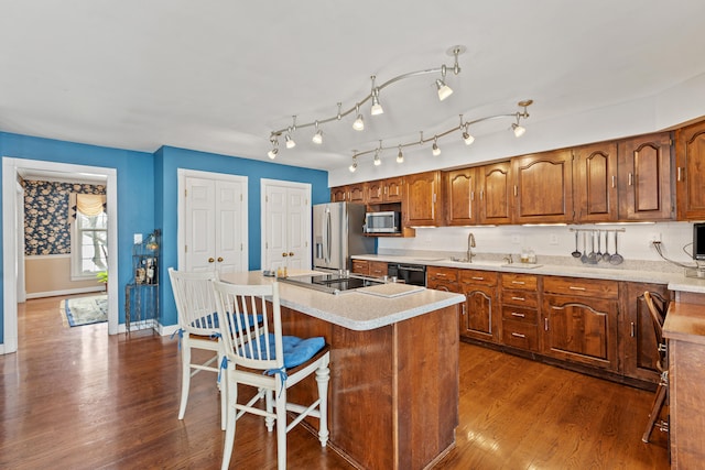 kitchen with sink, a kitchen bar, an island with sink, dark hardwood / wood-style flooring, and black appliances