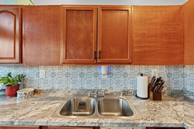 kitchen with light stone counters, sink, and backsplash