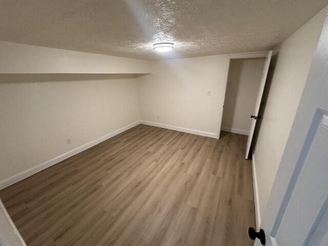 basement with a textured ceiling and light hardwood / wood-style floors