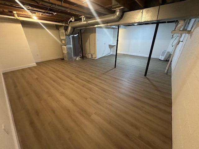 basement featuring heating unit and hardwood / wood-style flooring