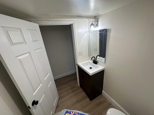 bathroom featuring toilet, hardwood / wood-style flooring, and vanity