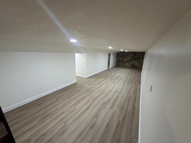 basement featuring a textured ceiling and light hardwood / wood-style flooring