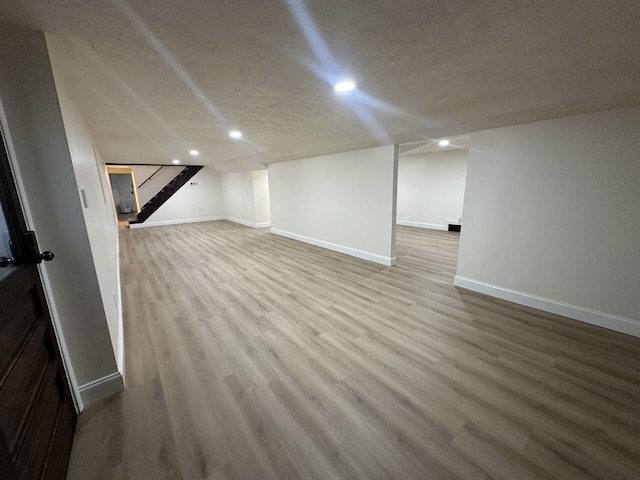 basement featuring a textured ceiling and light hardwood / wood-style floors