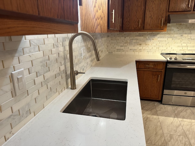 kitchen with stainless steel electric stove, decorative backsplash, and sink