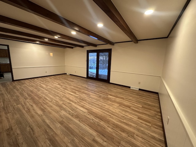 unfurnished room featuring hardwood / wood-style flooring and beam ceiling