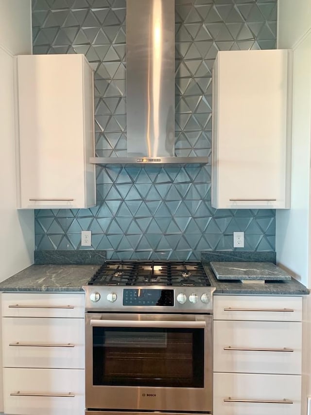 kitchen featuring white cabinetry, wall chimney range hood, decorative backsplash, and stainless steel gas range