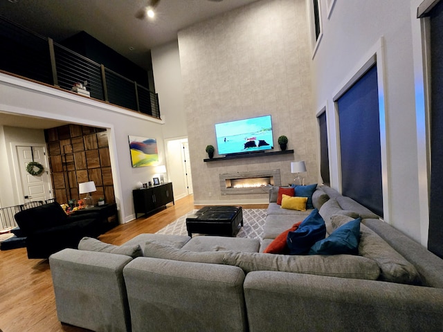 living room with a towering ceiling, a fireplace, and light hardwood / wood-style floors