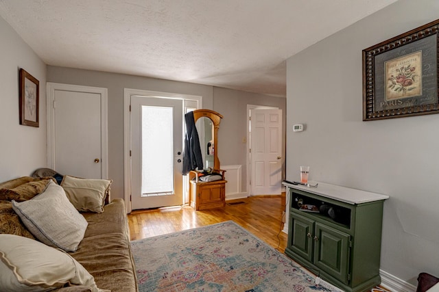 living room with a textured ceiling and light hardwood / wood-style floors