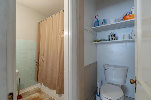 bathroom with toilet and tile walls