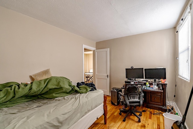 bedroom featuring a textured ceiling and light hardwood / wood-style flooring