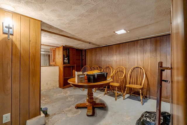 sitting room featuring wooden walls, a textured ceiling, and concrete flooring