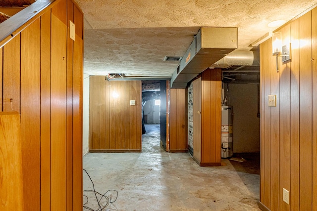 interior space with water heater, wood walls, and a textured ceiling