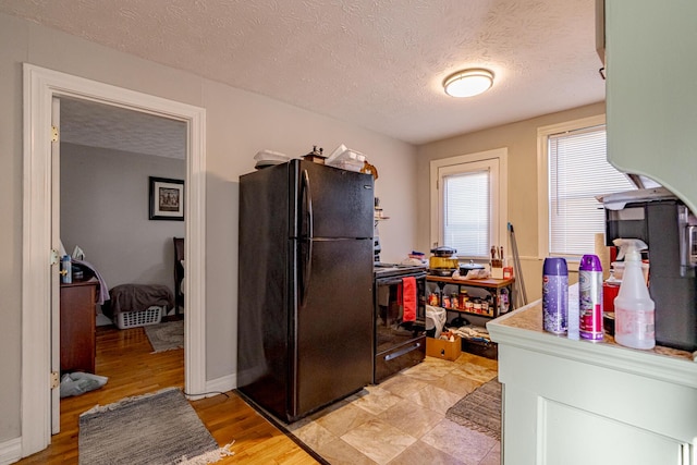 kitchen featuring a textured ceiling, black appliances, and light hardwood / wood-style flooring