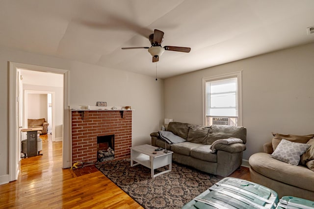 living room featuring wood-type flooring, a brick fireplace, ceiling fan, and cooling unit