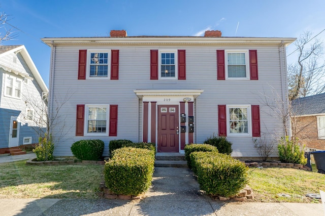 colonial-style house featuring a front lawn