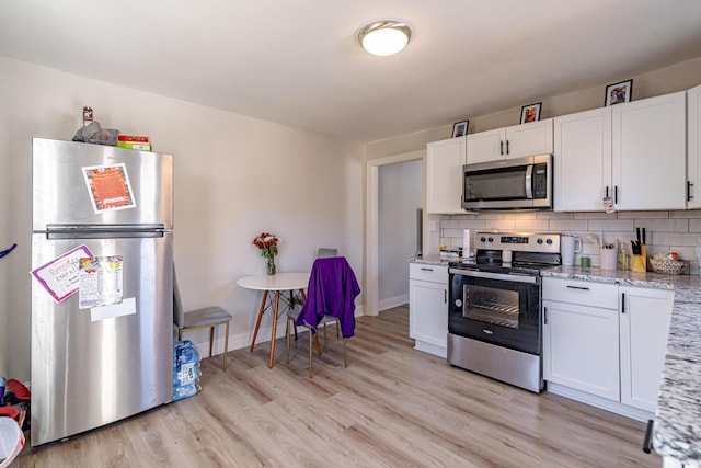 kitchen featuring light stone countertops, stainless steel appliances, decorative backsplash, light wood-type flooring, and white cabinetry