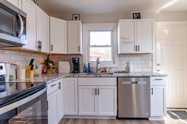 kitchen featuring sink, stainless steel appliances, light stone countertops, and white cabinetry